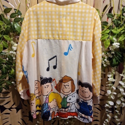Camisa amarela com padrão xadrez e estampa Peanuts na parte traseira