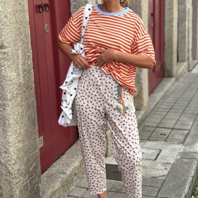 Mulher com roupas coloridas num ambiente urbano junto a portas vermelhas
