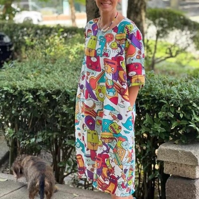 Mulher com vestido colorido de desenhos animados, óculos escuros, sapatos azuis, com cão ao lado ao ar livre