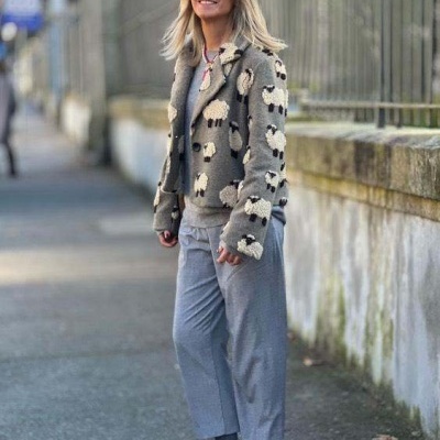 Mulher com casaco de ovelhas, calças cinzentas, sapatos vermelhos e óculos de sol vermelhos na rua