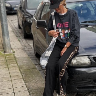 Mulher com roupas casuais com padrão de leopardo e boné preto sentada num carro preto