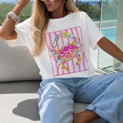 Mulher com t-shirt branca estampada, calças de ganga claras e chapéu de palha