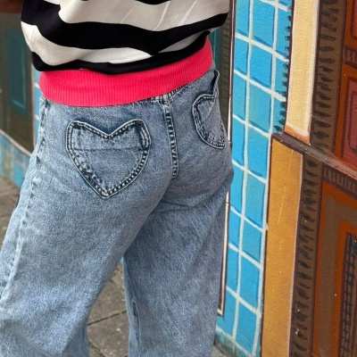 Jeans ganga com bolsos em coração e camisola às riscas junto a azulejos azuis