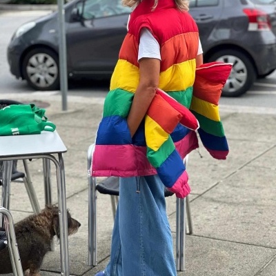 Pessoa com casaco acolchoado colorido e calças largas azuis no passeio