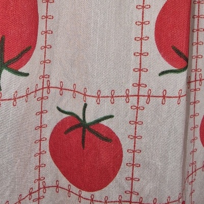 Tecido branco com padrão de tomates vermelhos e folhas verdes bordado em linhas vermelhas