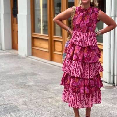 Mulher com vestido midi estampado rosa vermelho, sandálias e acessórios.