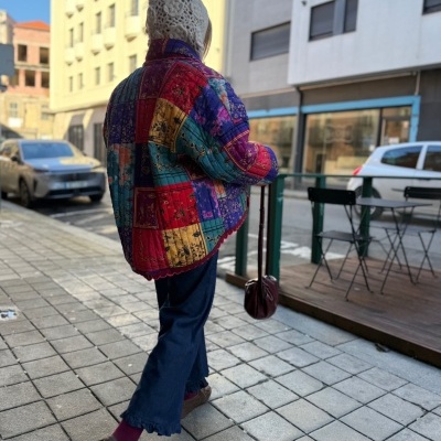 Pessoa de costas com casaco acolchoado colorido numa rua urbana