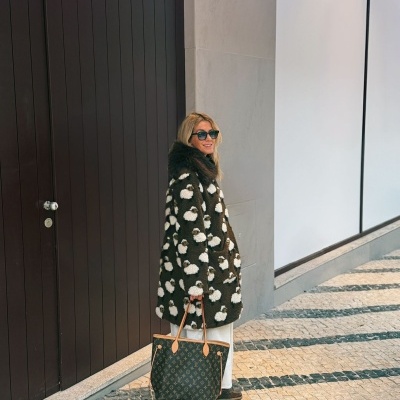 Mulher com casaco peludo verde escuro com padrão branco, mala Louis Vuitton castanha e óculos escuros