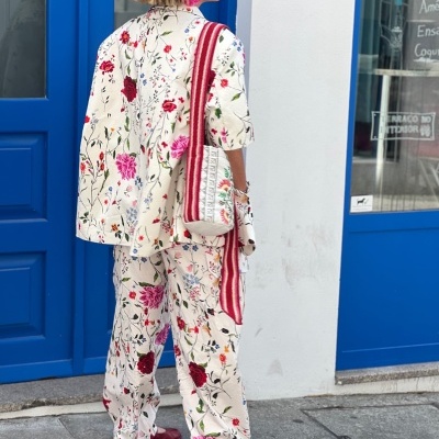 Conjunto floral com blazer, calças largas e bolsa na rua junto a porta azul
