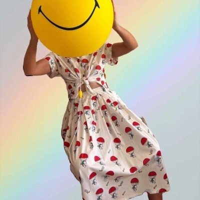 Vestido branco com padrão de guarda-chuvas vermelhos e bola amarela sorridente