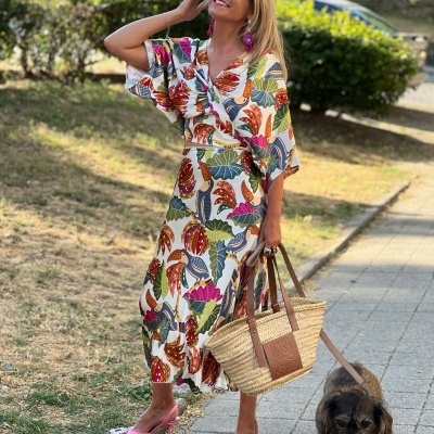 Mulher com vestido longo estampado a andar na rua com cão ao lado