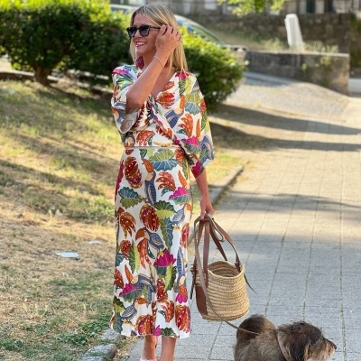 Mulher com vestido colorido a passear cão num passeio pavimentado