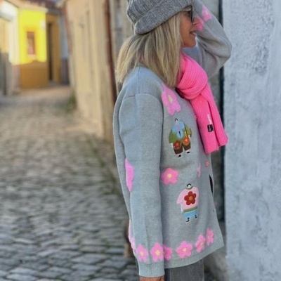 Mulher com casaco cinzento colorido e acessórios de inverno na rua com calçada de pedra