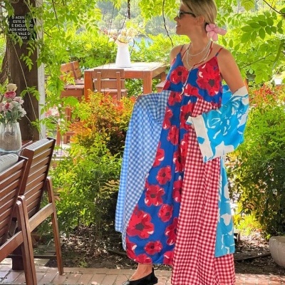Vestido comprido colorido com vários padrões usado por mulher com flor no cabelo e óculos escuros