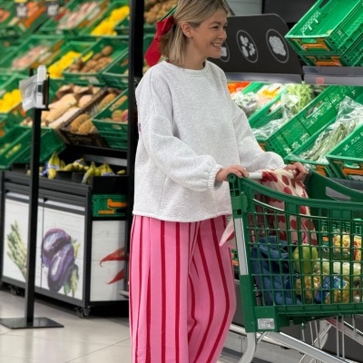 Mulher a fazer compras no supermercado com roupa casual e carrinho verde cheio de vegetais