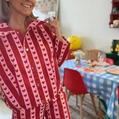 Pijama de algodão vermelho e rosa com corações e riscas usado por mulher sorridente
