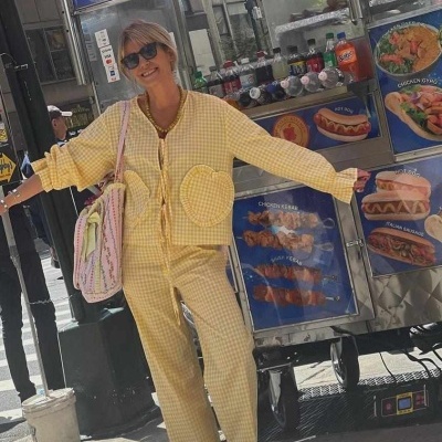 Pessoa de amarelo com padrão xadrez junto a carrinho de comida de rua