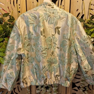 Casaco feminino em tecido jacquard floral com mangas compridas pendurado