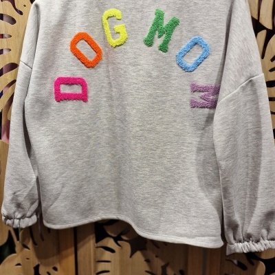 Sweatshirt cinzenta com letras coloridas DOG MOM pendurada num cabide de madeira