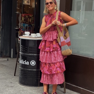 Mulher com vestido rosa e carteira de crochet colorida na rua