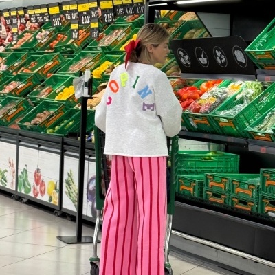 Mulher no supermercado a escolher legumes ao lado de caixas verdes