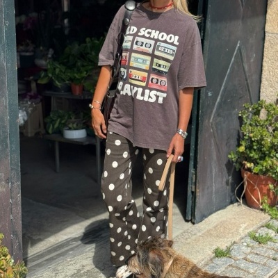 Mulher com roupa casual colorida e cão castanho à trela em porta antiga
