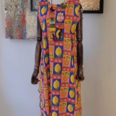 Vestido longo colorido com padrão de frutas num manequim de madeira