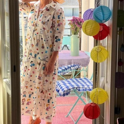 Vestido comprido branco com padrão colorido, usado numa porta com varanda ao fundo decorada