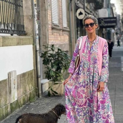 Mulher com vestido floral e colete rosa com cão na calçada