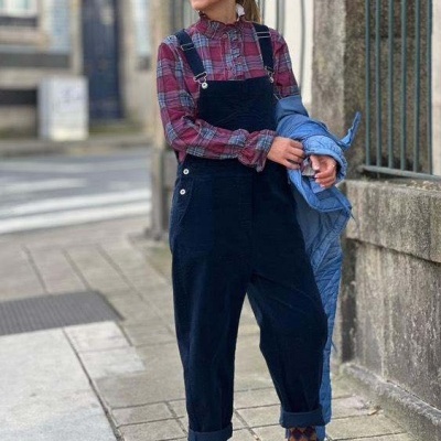 Mulher com macacão azul e camisa xadrez numa rua