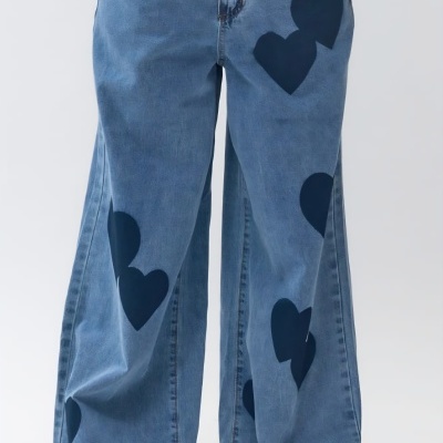 Calças de ganga azuis com corações pretos e calçado branco.