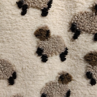 Tecido felpudo com padrão de ovelhas em tons bege e castanho sobre fundo creme
