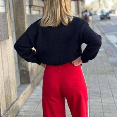 Pessoa de costas com casaco preto e calças vermelhas na rua