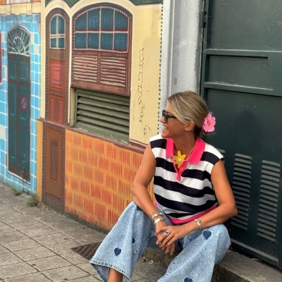 Pessoa sentada com roupa casual colorida e mural de portas pintadas ao fundo