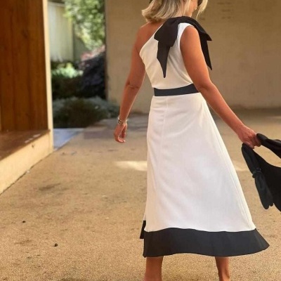 Vestido branco e preto com gola em laço, usado por mulher em ambiente exterior