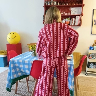 Pessoa de pijama com padrão de corações vermelhos em ambiente doméstico com mesa e cadeira vermelhas