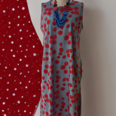 Vestido cinza com padrão vermelho exibido num manequim com colares coloridos