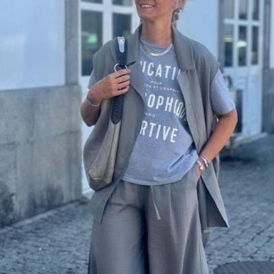 Mulher com roupa casual cinzenta numa rua de calçada