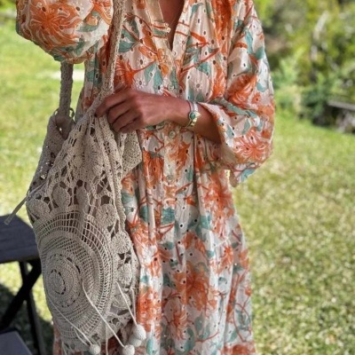 Vestido floral comprido e bolsa de croché bege num jardim
