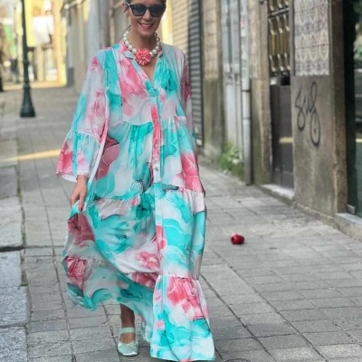 Mulher com vestido longo floral colorido numa rua de calçada