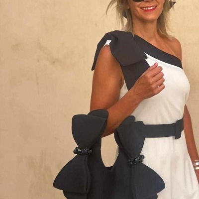 Mala preta arredondada com detalhes e mulher vestindo branco e preto