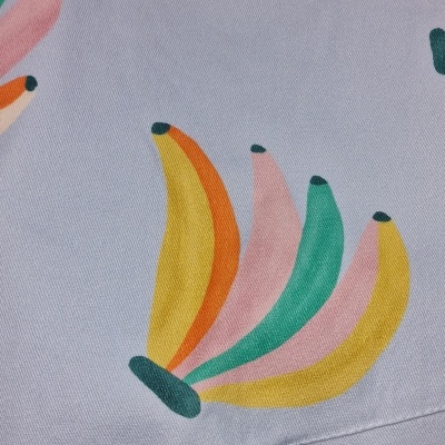 Tecido lilás com padrão colorido de bananas estilizadas