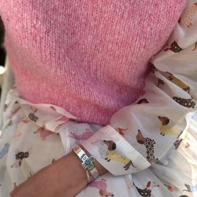 Pullover rosa de malha com camisa estampada com cães coloridos e pulseira prateada