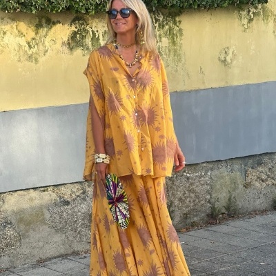 Conjunto amarelo floral com saia longa e blusa solta em mulher com acessórios, ao ar livre