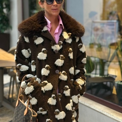 Mulher com casaco de ovelhas, óculos escuros e mala Louis Vuitton.