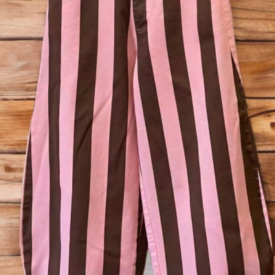 Calças largas riscas rosa e castanho com cintura alta em fundo de madeira