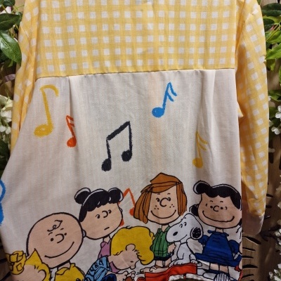 Blusão amarelo com xadrez branco e personagens Peanuts na parte inferior