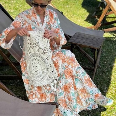 Vestido floral longo e bolsa de crochê branca em cadeira de jardim