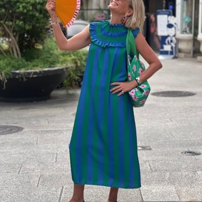 Vestido comprido azul e verde com folhos, leque laranja, sapatilhas azuis e bolsa verde com flores.