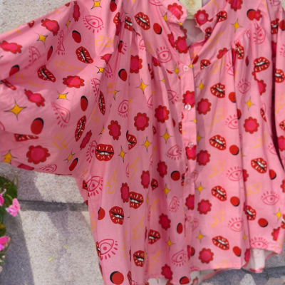 Blusa rosa com padrão colorido pendurada num cabide preto